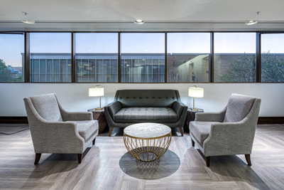 Seating area with a sofa and 2 chairs with windows that give a view of the Taggart Student Center.